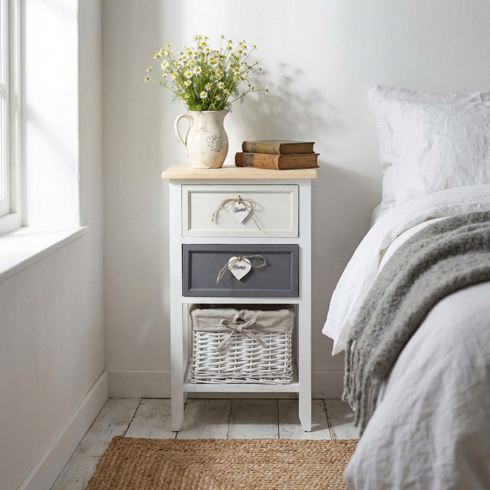 Comodino Andres shabby chic ambientato accanto a un letto con vaso di fiori.
