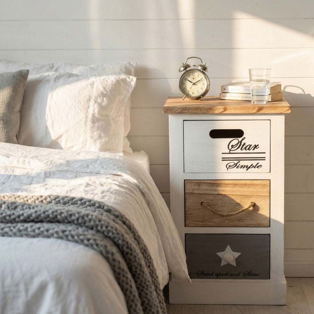 Comodino shabby chic Blas ambientato in una luminosa camera da letto accanto a coperte in lino.