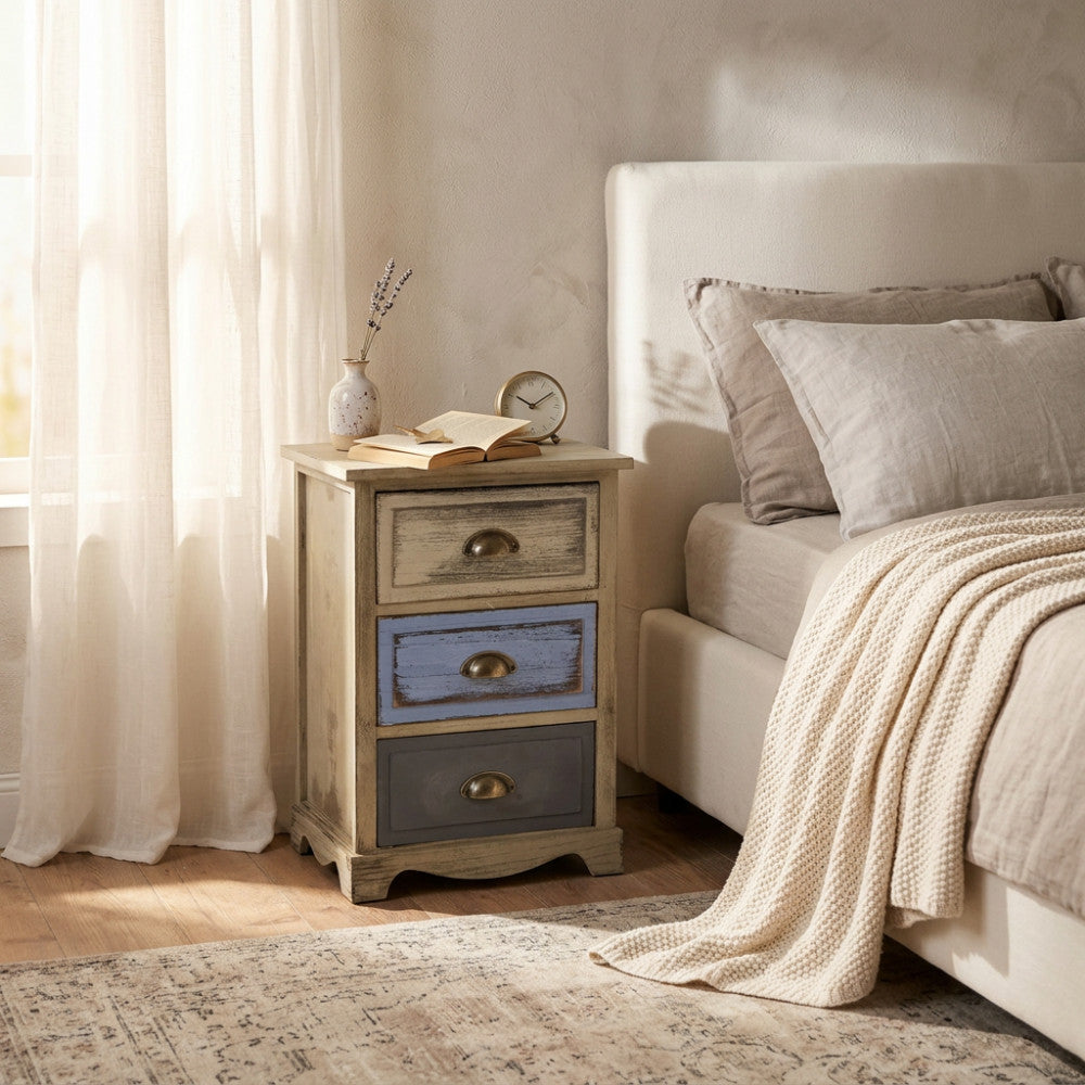 Comodino shabby chic Chico grigio e turchese posizionato accanto a un letto matrimoniale in una camera luminosa.