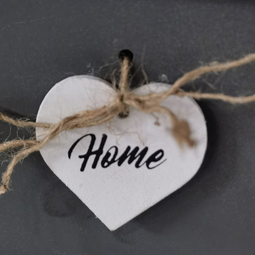Primo piano del pendente decorativo a forma di cuore con la scritta Home e cordino in iuta grezza.