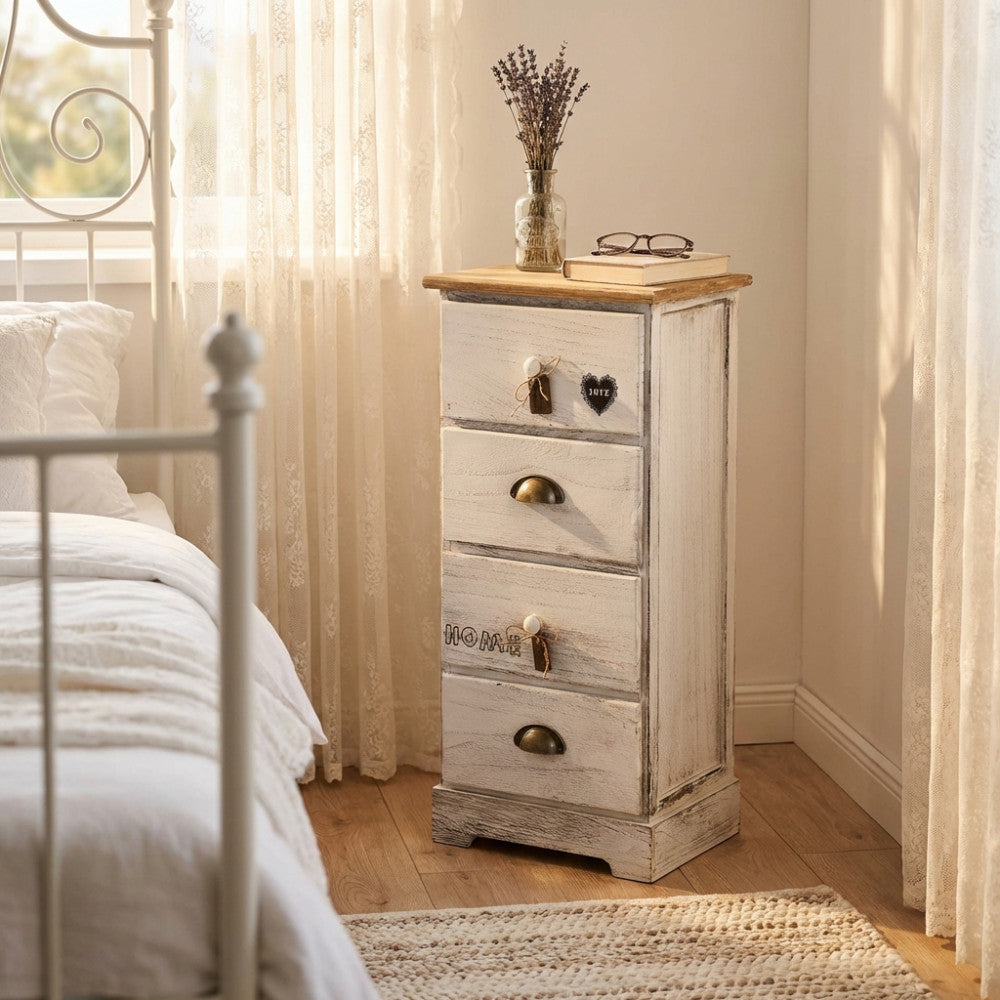 Mobiletto ANDER a 4 cassetti in legno decapé bianco, ambientato in una luminosa camera da letto shabby chic accanto a un letto in ferro battuto.