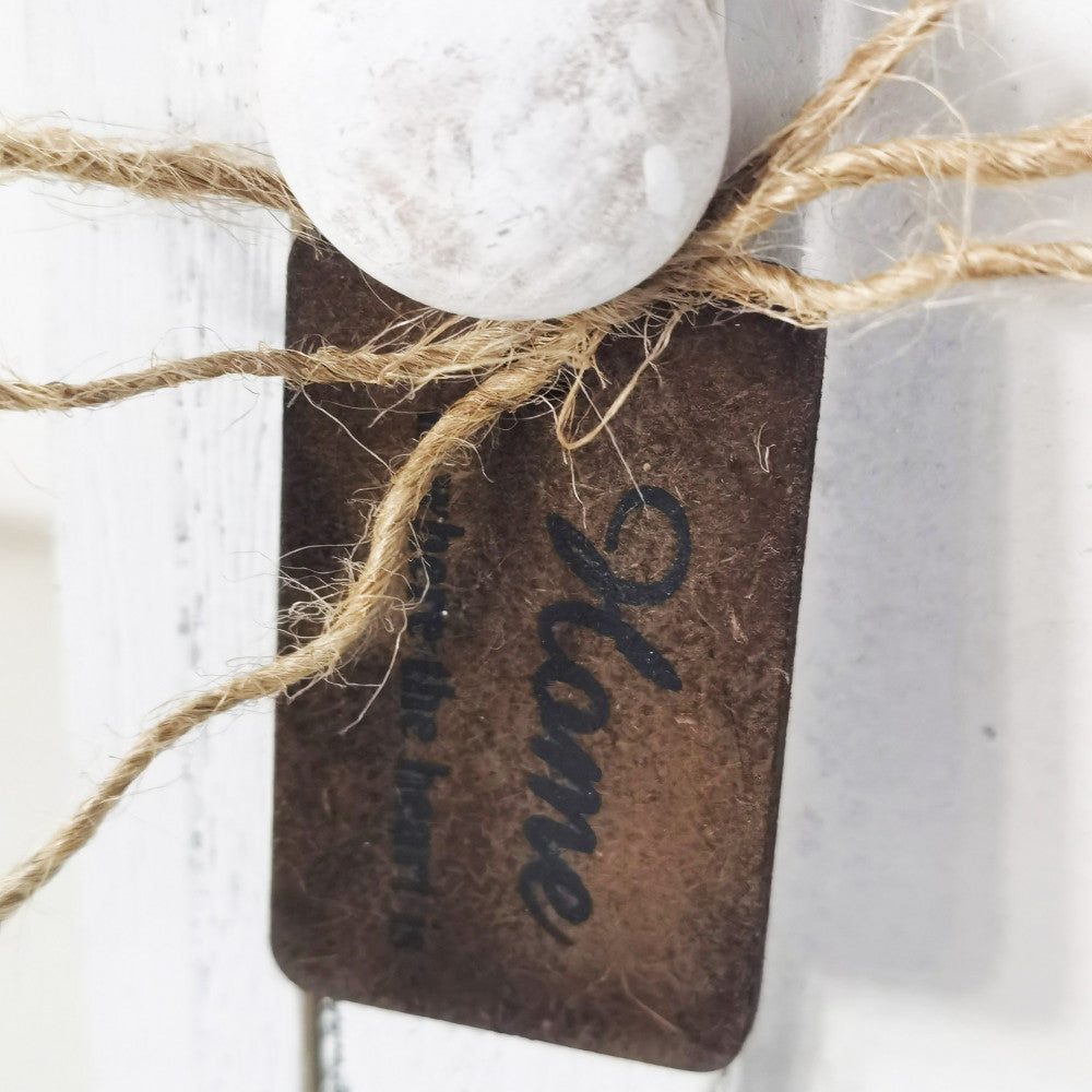 Macro dettaglio tattile del cassetto superiore, con focus sul pomello bianco, il fiocco in corda grezza e l'etichetta decorativa.