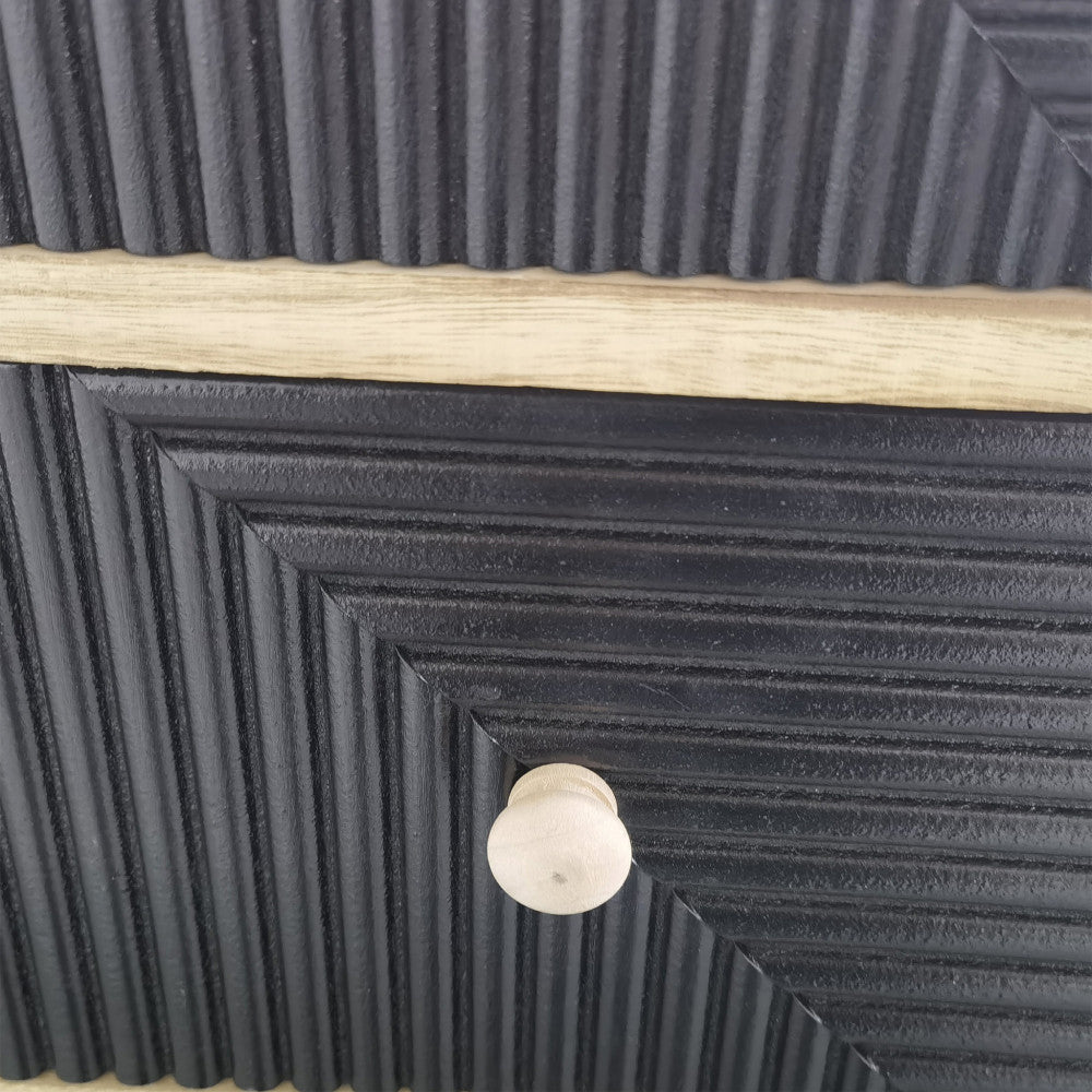 Dettaglio ravvicinato della texture scanalata diagonale dei cassetti neri e del pomello in legno.