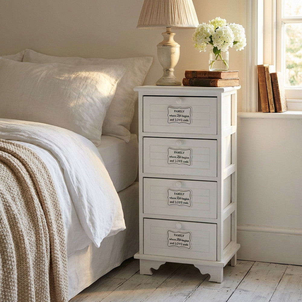 Comodino shabby chic bianco Biel posizionato accanto a un letto con lampada e fiori.