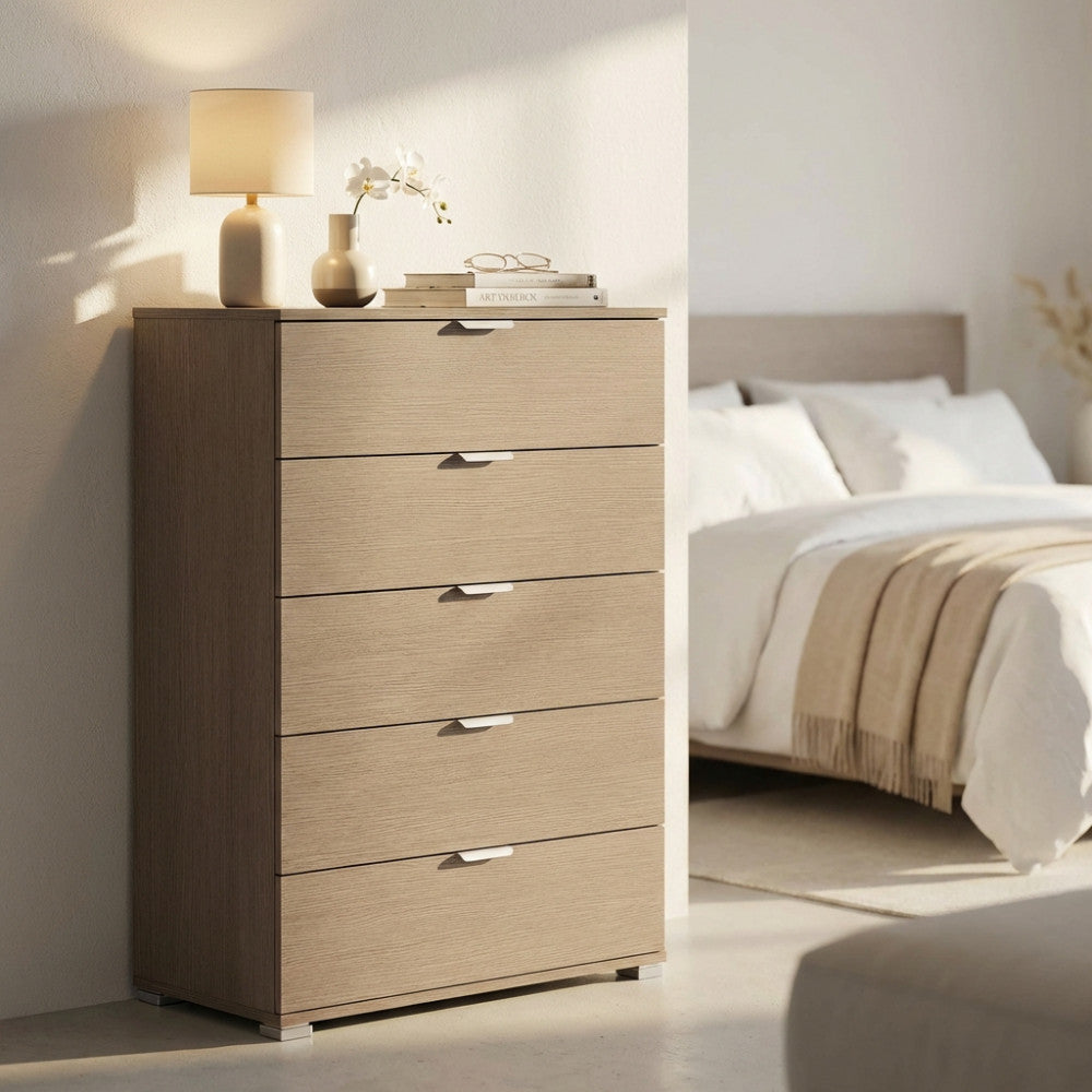 Cassettiera a cinque cassetti in rovere grigio ambientata in una luminosa camera da letto con luce naturale.