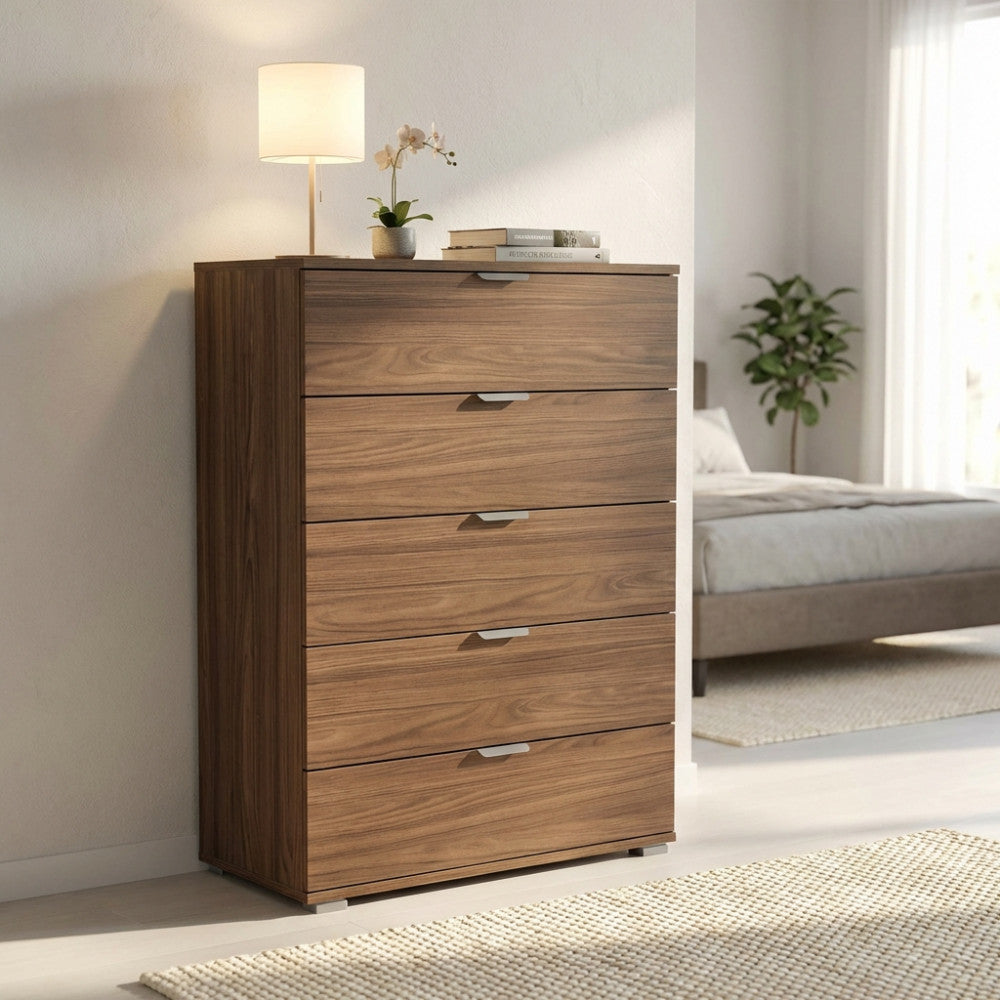 Vista angolare della cassettiera marrone con maniglie minimaliste in metallo accanto a un letto matrimoniale.
