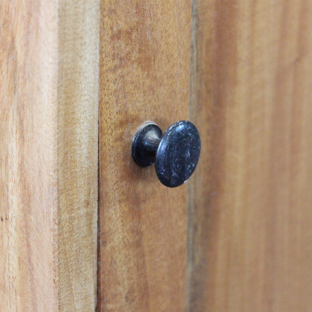 Dettaglio ravvicinato del pomello scuro e della venatura del legno marrone sulla superficie del mobiletto Caleb.