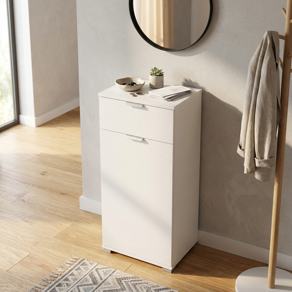 Dettaglio del mobiletto bianco con anta e cassetto, illuminato dalla luce naturale accanto a un appendiabiti in legno.