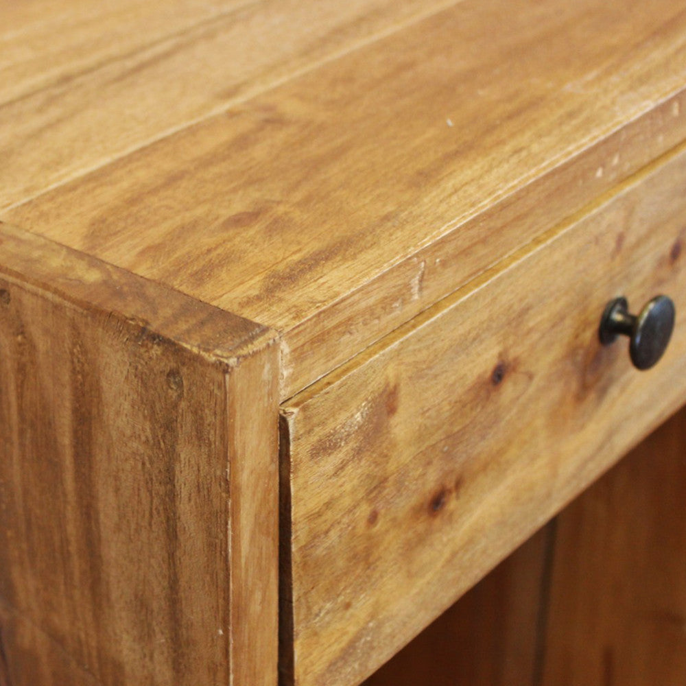Dettaglio ravvicinato dello spigolo superiore e del pomello in metallo scuro sul legno venato.