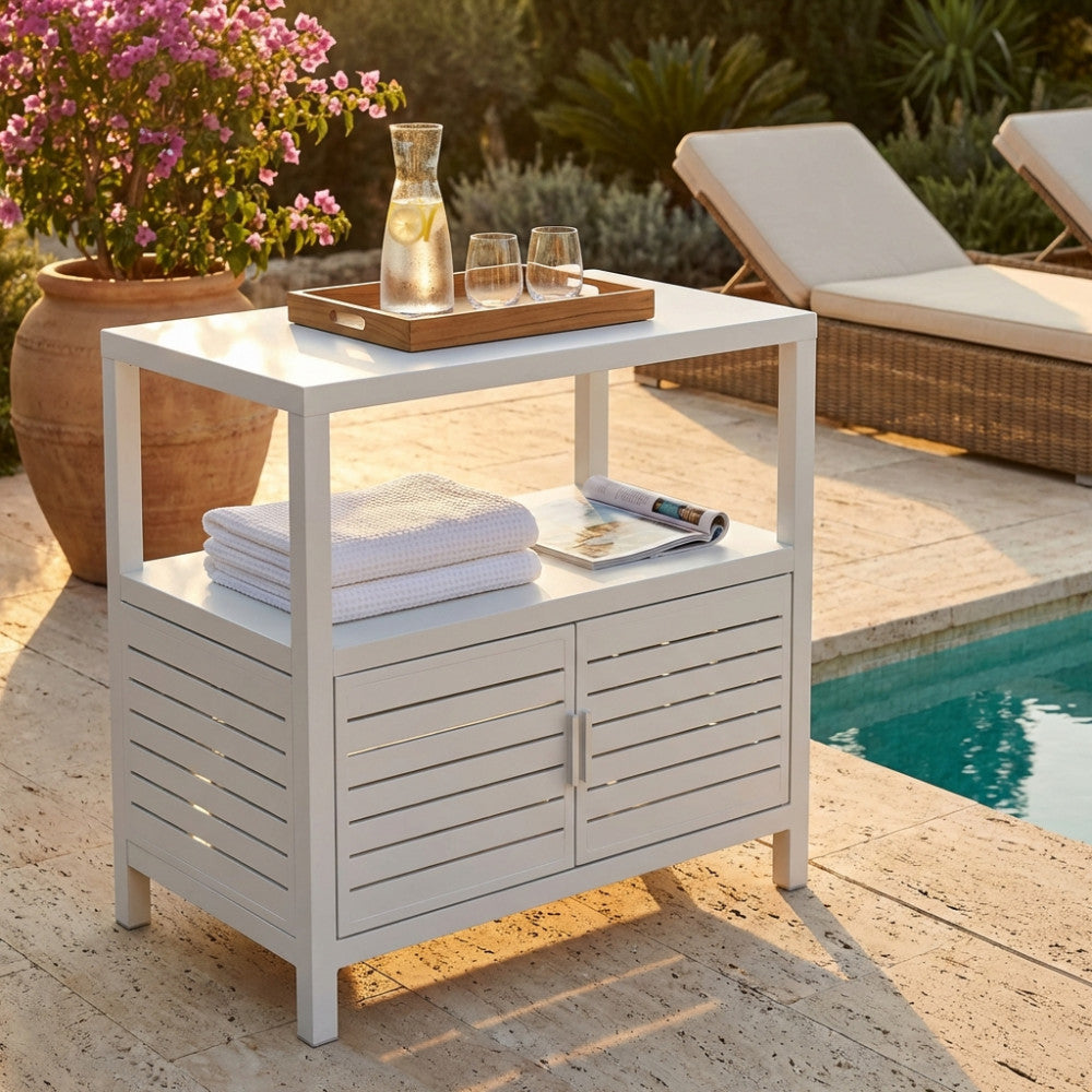 Mobiletto Phoenix in alluminio bianco a bordo piscina, allestito con vassoio in legno, caraffa d'acqua e asciugamani bianchi.