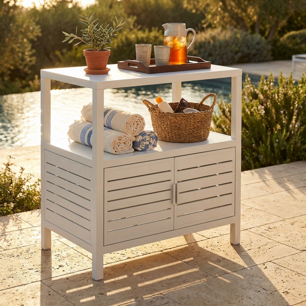 Credenza outdoor Phoenix bianca con cesto in vimini, teli mare arrotolati e bevande fresche su una terrazza soleggiata.