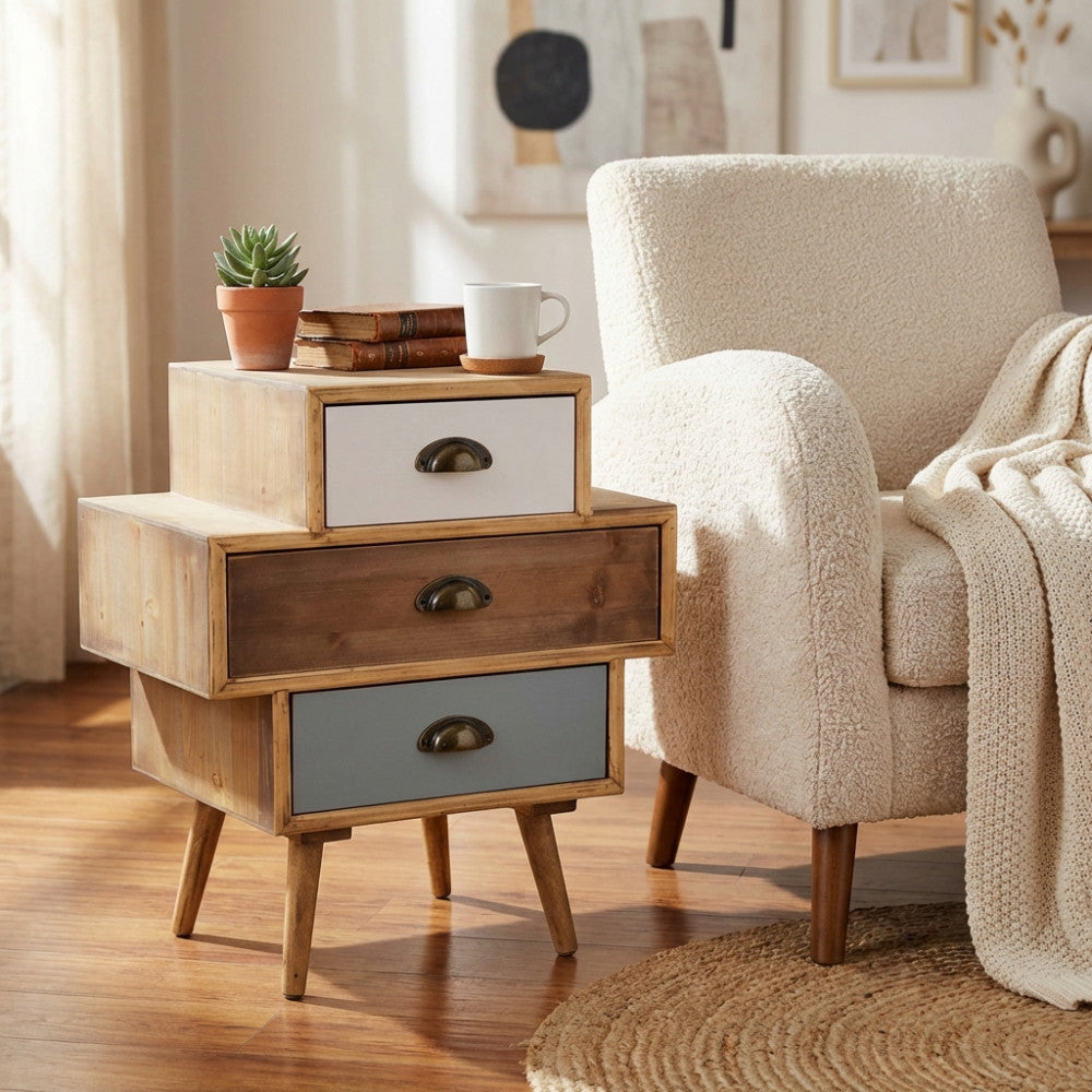 Cassettiera shabby chic Victoria posizionata vicino a una poltrona in boucle bianco con luce naturale.