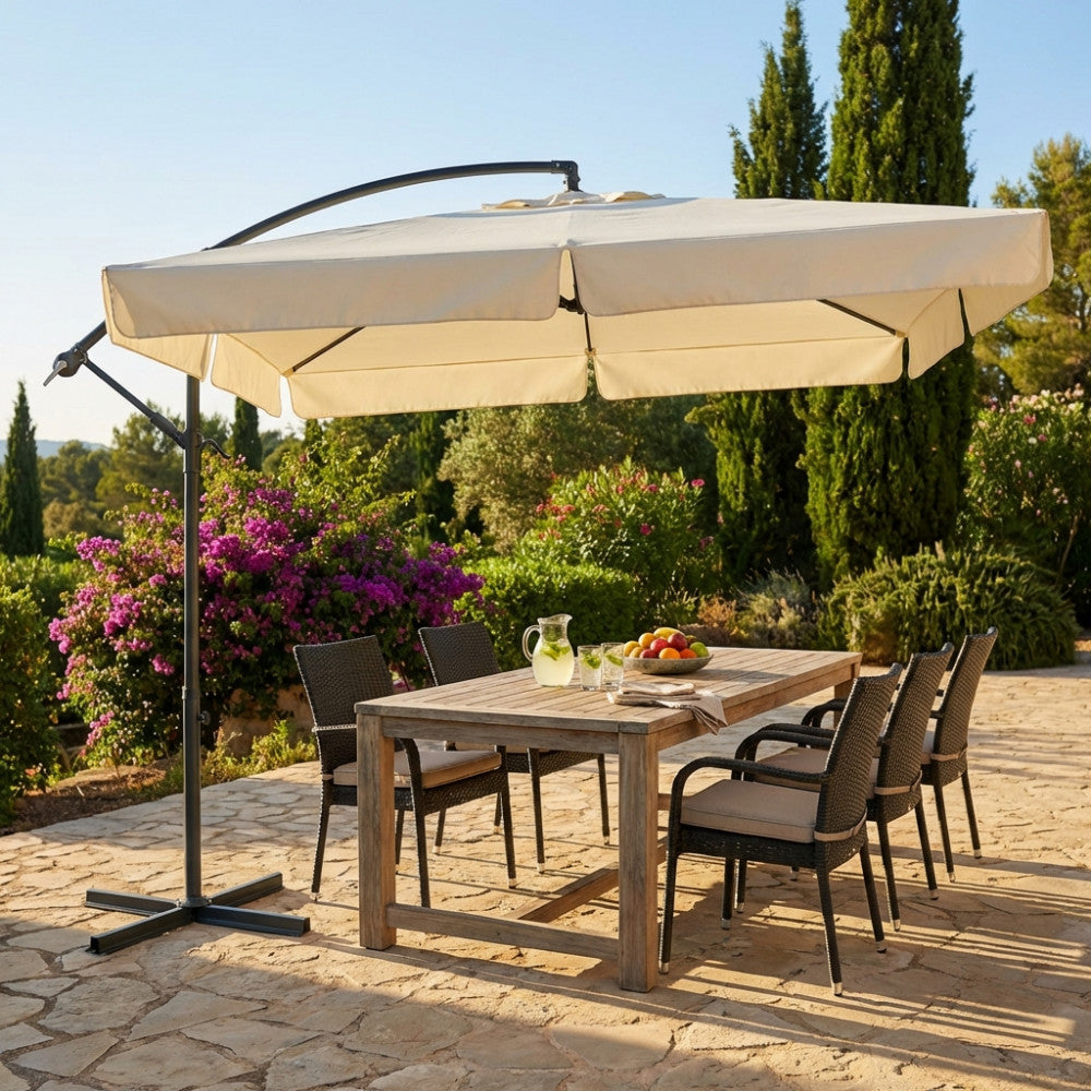 Ombrellone quadrato Almeria 2,5 x 2,5 metri che copre un grande tavolo da pranzo in legno e sedie in rattan in un patio soleggiato.