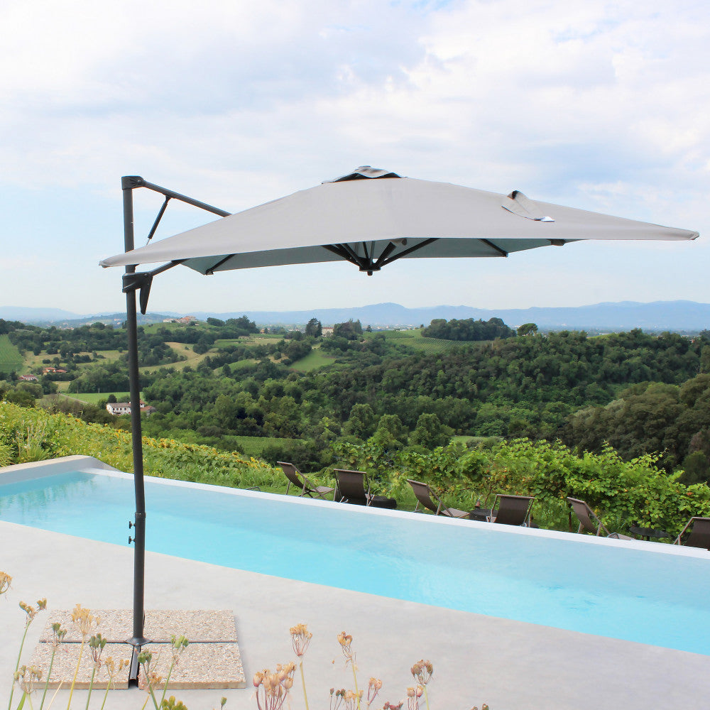 Ombrellone Altair aperto in un giardino panoramico con piscina a sfioro.