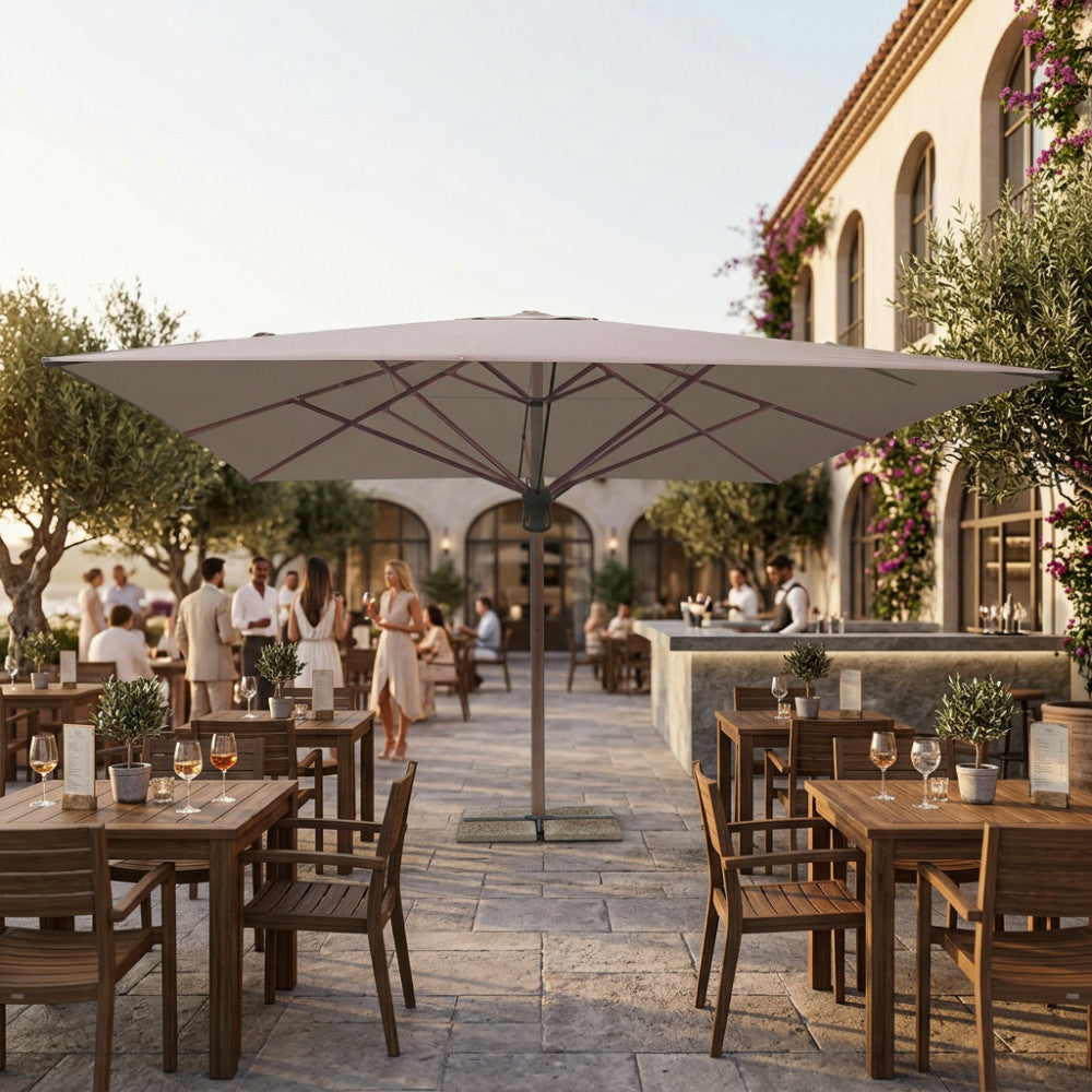 Ombrellone a palo centrale Arneb 5x5 metri in alluminio effetto legno e telo taupe, allestito in un elegante patio di un ristorante all'aperto.