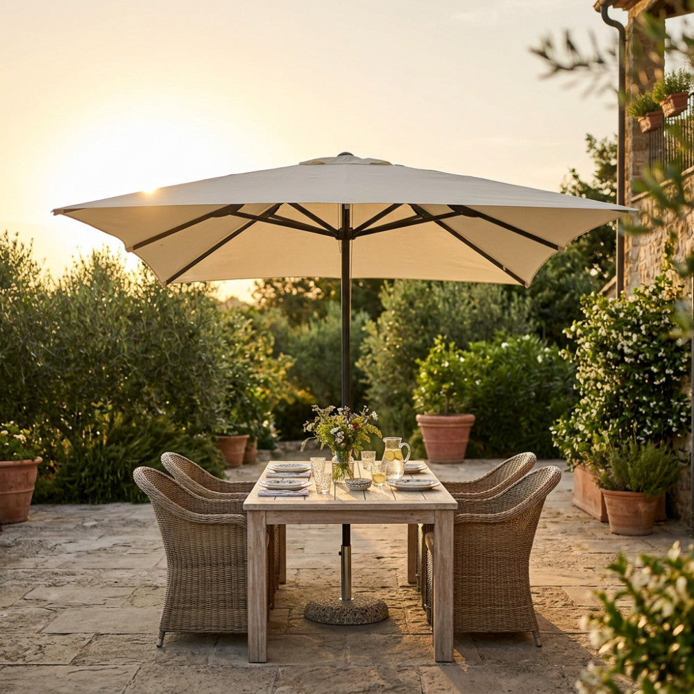 Ombrellone a palo centrale aperto su un tavolo da pranzo in un giardino al tramonto.