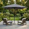 Ombrellone Brian aperto in un giardino lussuoso con due poltrone lounge.