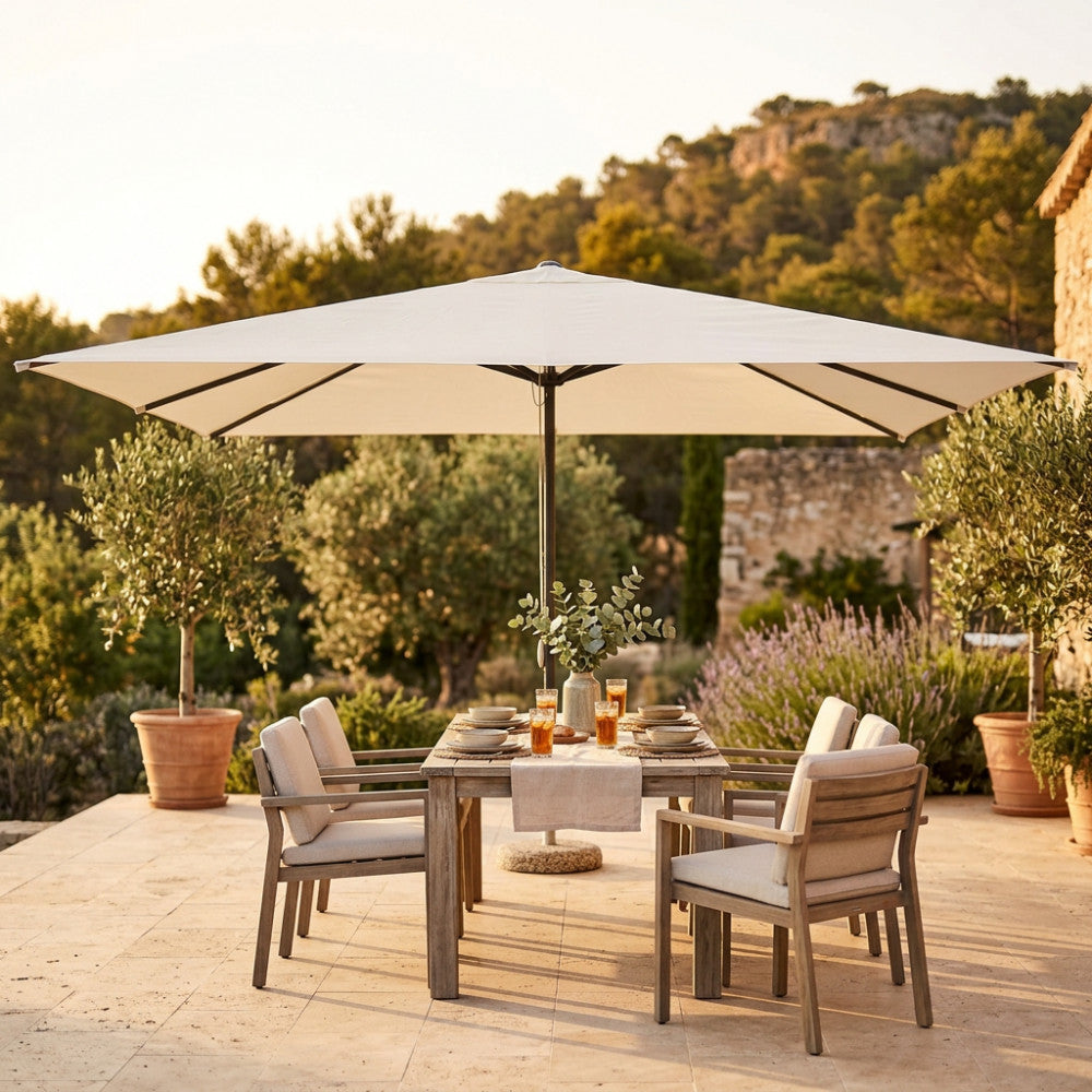 Ombrellone Brian 3x4 aperto su un tavolo da pranzo in legno in un giardino mediterraneo.