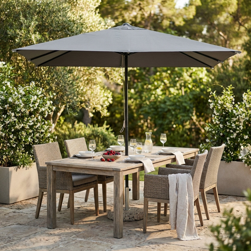 Dettaglio dell'ombrellone Brian che ombreggia un elegante tavolo da pranzo in legno all'aperto.
