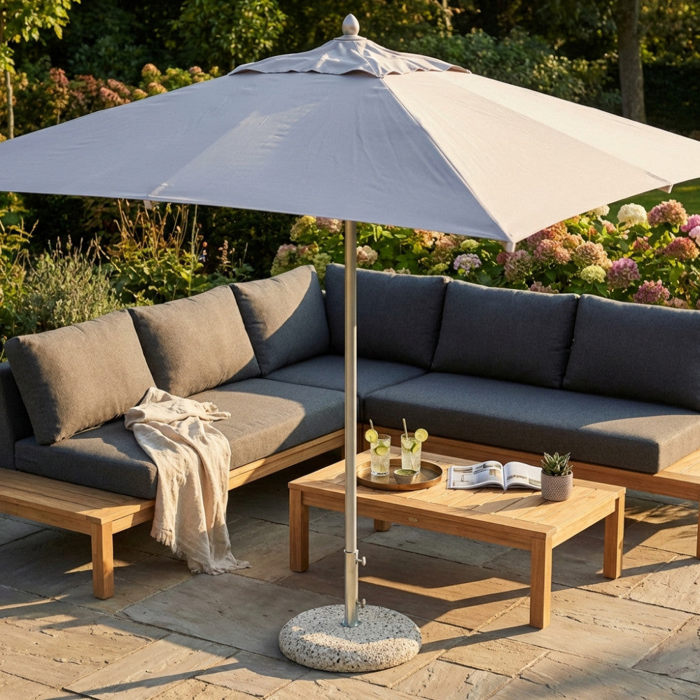 Dettaglio dell'ombrellone Cristal aperto, che proietta un'ombra elegante su un divano angolare da giardino e un tavolino in teak.