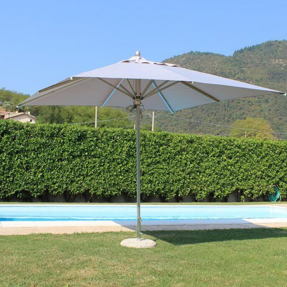 Ombrellone Cristal completamente aperto a bordo piscina, che mostra la tensione perfetta del telo e la robustezza della base in pietra.