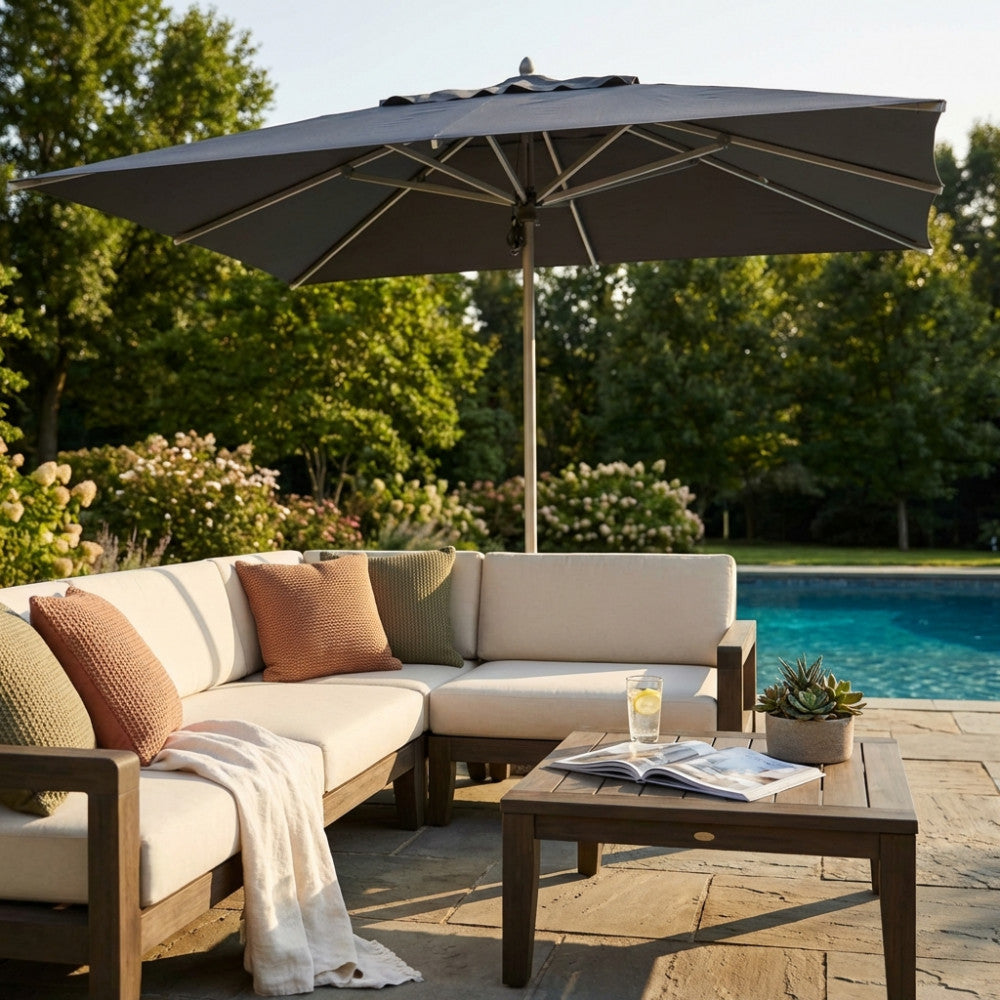 Ombrellone Cristal 3x4 grigio aperto su un salotto da esterni con divano beige e piscina.