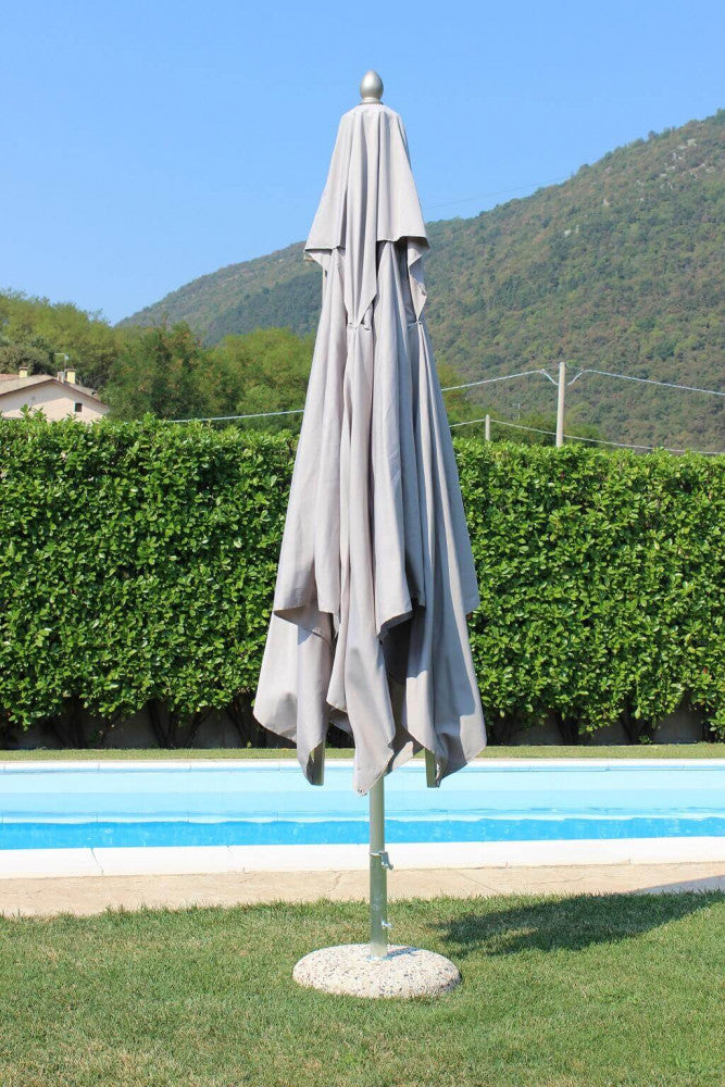 Ombrellone da giardino chiuso con telo in poliestere grigio chiaro ripiegato lungo il palo centrale in alluminio, posizionato a bordo piscina.