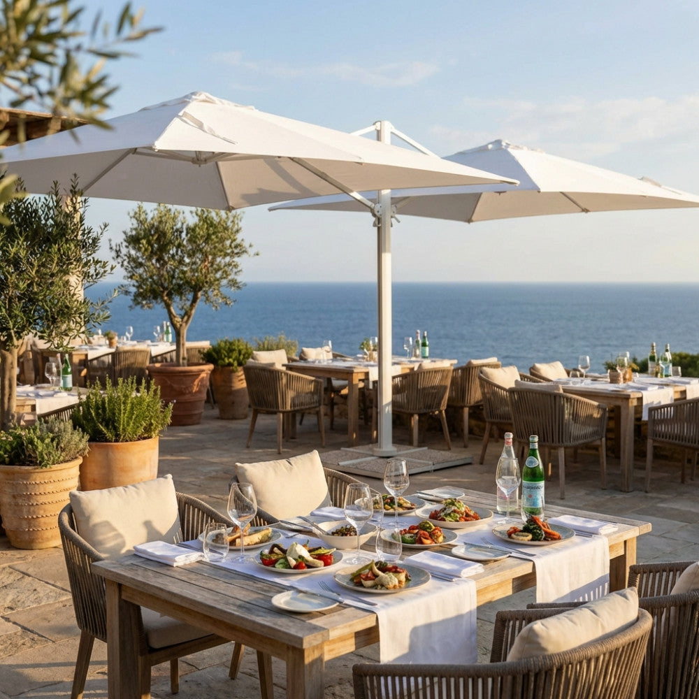 Dettaglio dell'ombrellone doppio Archimede che ombreggia tavoli eleganti in un ristorante costiero.