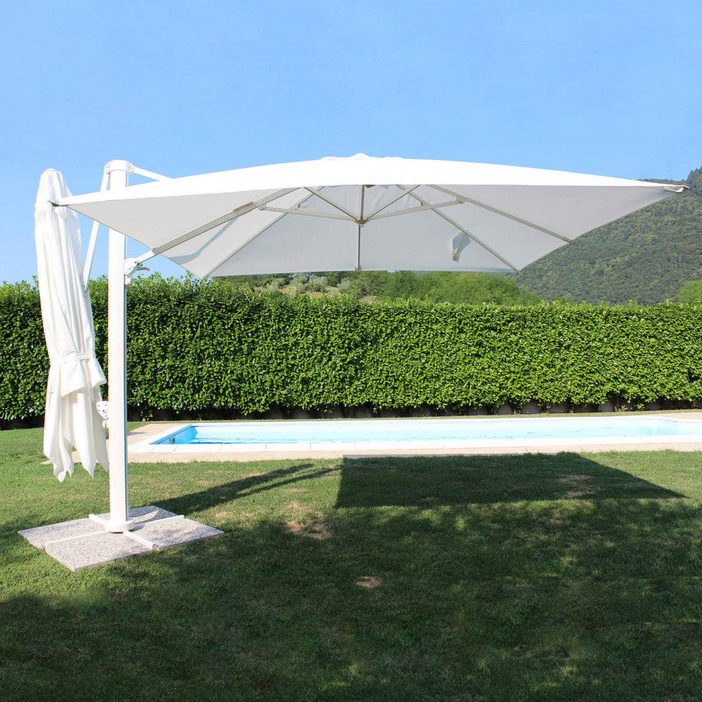 Ombrellone doppio Archimede bianco a bordo piscina in un giardino lussureggiante.