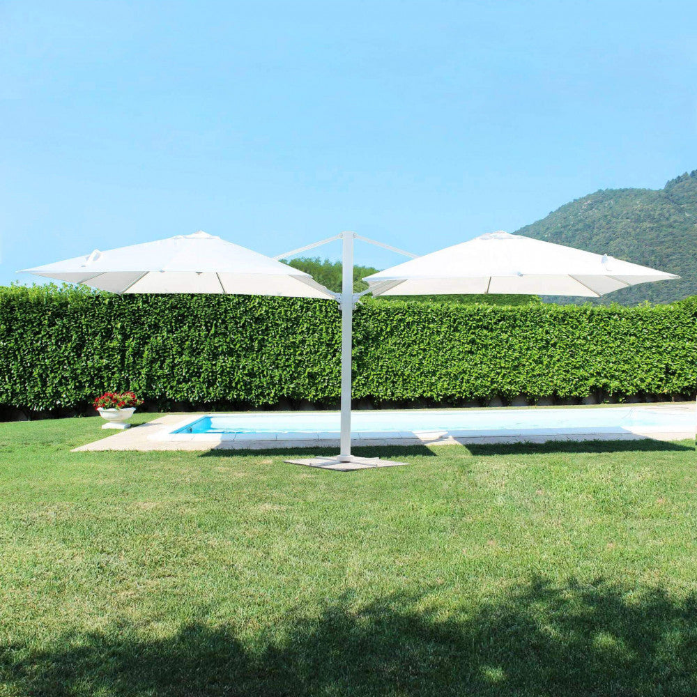 Ampia vista dell'ombrellone doppio Archimede aperto su un prato verde vicino a una piscina.