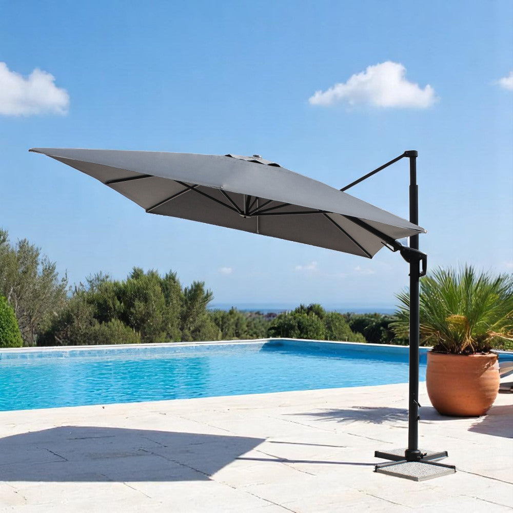 Ombrellone grigio scuro aperto in un patio soleggiato vicino a una piscina azzurra.