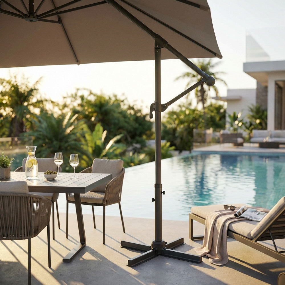 Ombrellone Nettuno Lux aperto a bordo piscina, con struttura in alluminio nero e telo taupe, che ombreggia un tavolo da pranzo elegante.