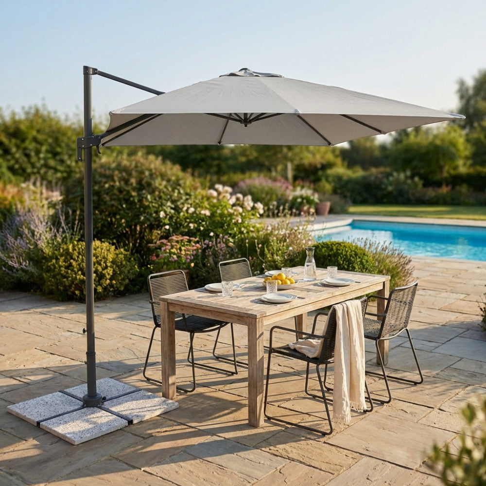 Elegante ombrellone rettangolare grigio che fa ombra su un tavolo in legno in un rigoglioso giardino estivo.