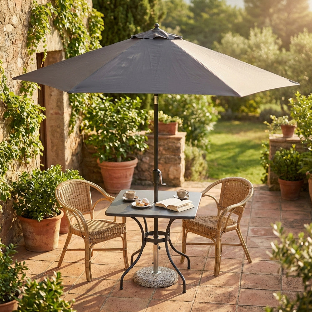 Ombrellone da esterno Nice aperto sopra un tavolino da bistrot con due sedie in vimini in un patio soleggiato.