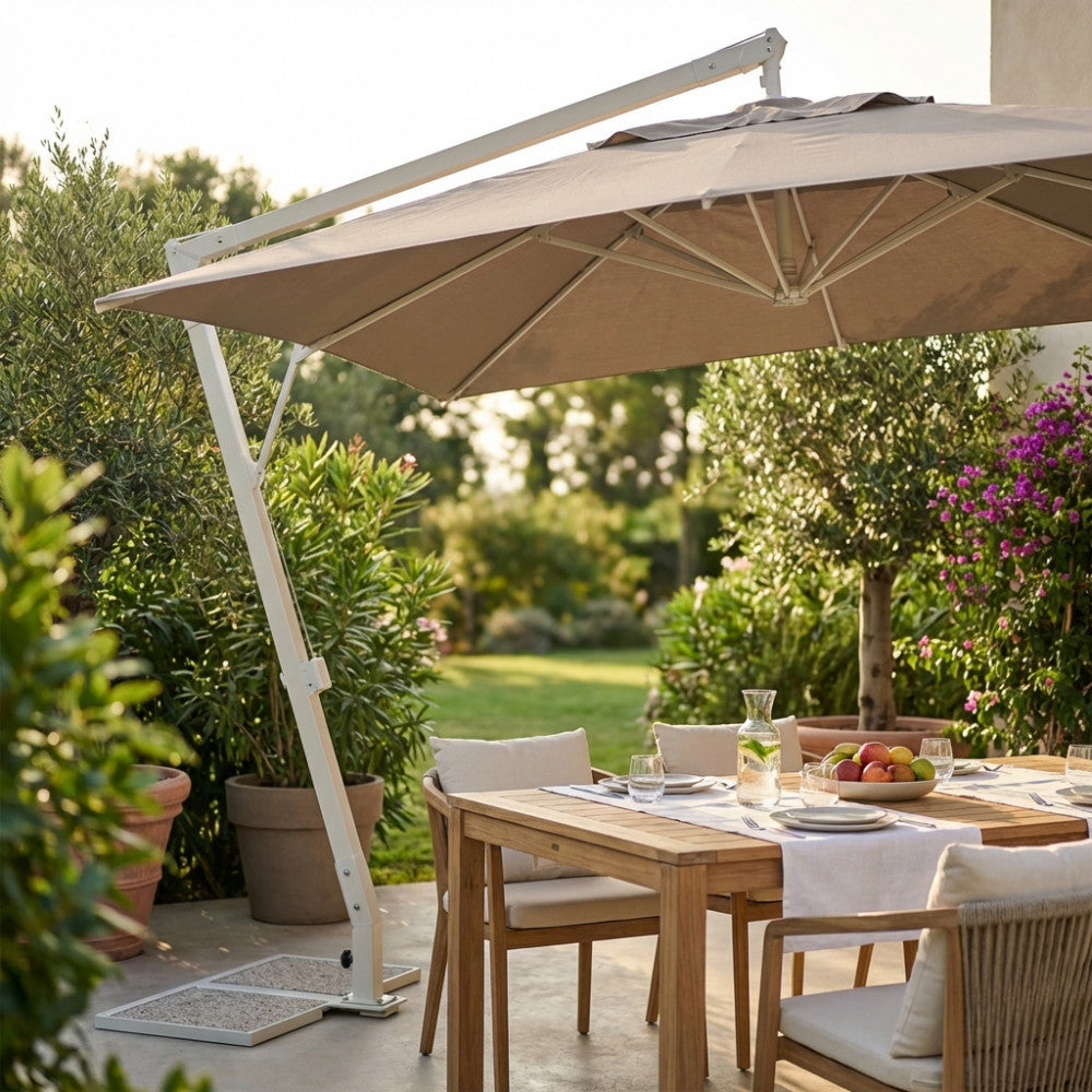 Ombrellone Pegaso 300x300 cm che ombreggia un elegante tavolo da pranzo in legno in un giardino rigoglioso.