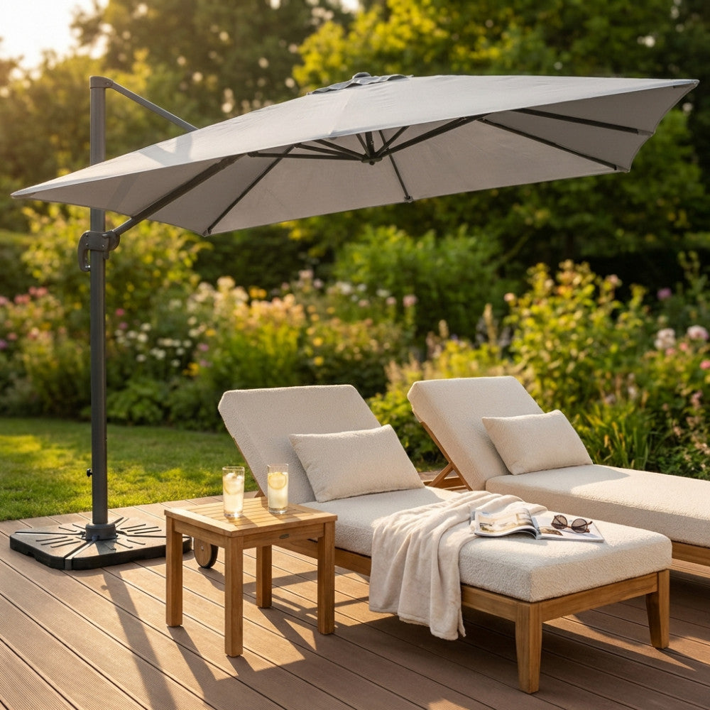 Ombrellone Saturno in alluminio antracite e poliestere grigio aperto su un giardino con lettini lounge.