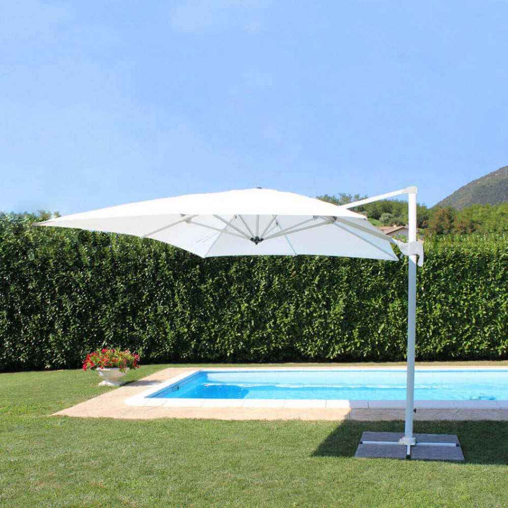 Ombrellone bianco a palo laterale posizionato su un prato verde accanto a una piscina azzurra.