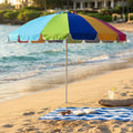 Ombrellone da spiaggia multicolor aperto sulla sabbia con telo mare a righe blu e bianche, occhiali da sole e libro.
