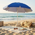 Ombrellone da spiaggia blu OM807041 aperto sulla sabbia, con telo mare, occhiali da sole e borsa in paglia.