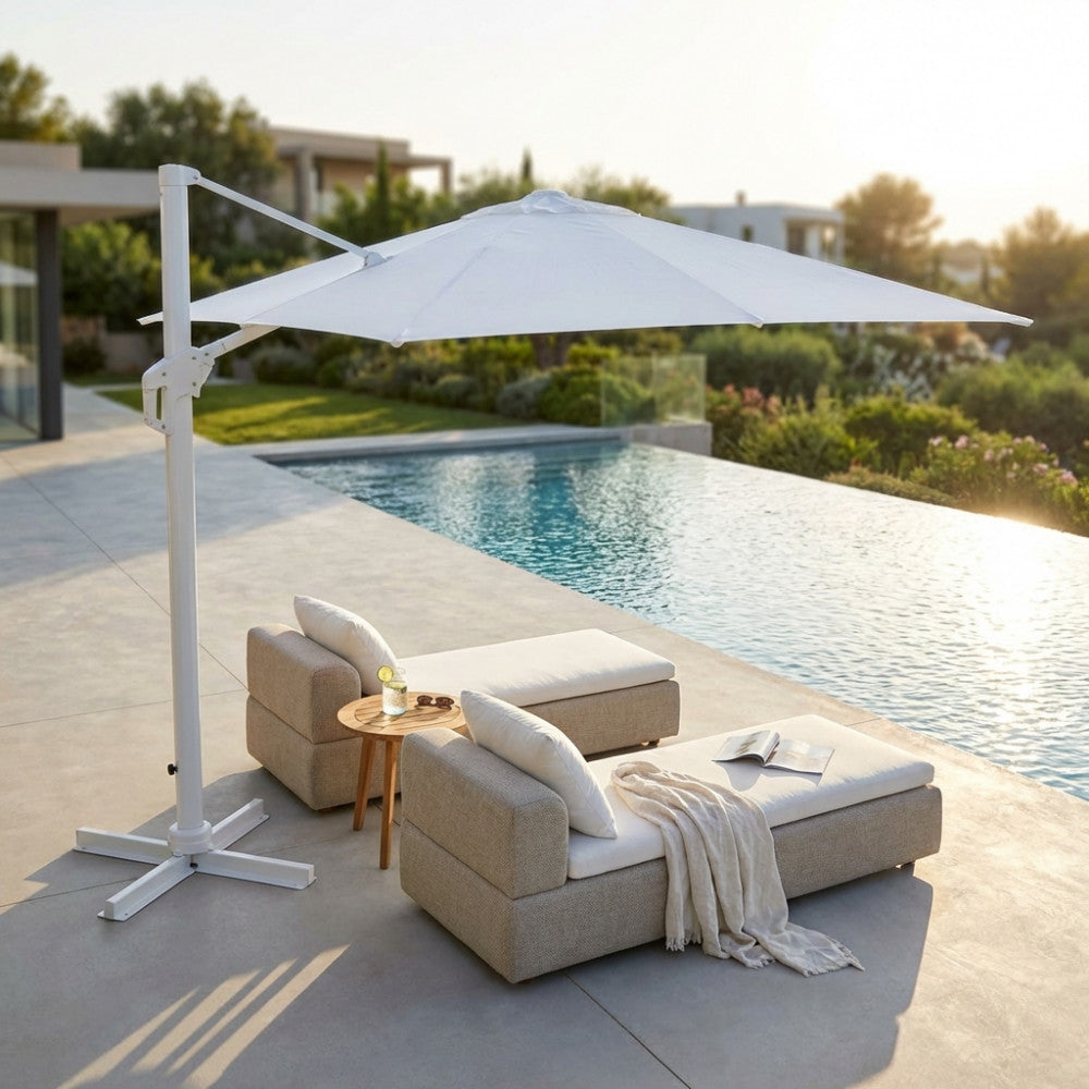 Ombrellone a palo laterale moderno bianco sopra due eleganti chaise longue imbottite vicino all'acqua.