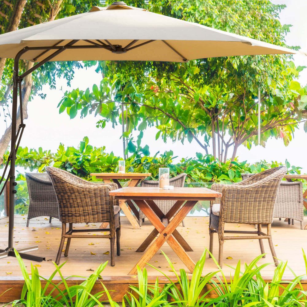 Ombrellone Zenith che ripara un'area lounge in legno con sedute in rattan in un lussuoso resort tropicale.