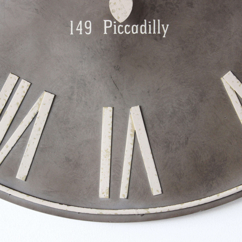 Dettaglio ravvicinato dei numeri romani e della scritta 149 Piccadilly sull'orologio da parete HUGO.