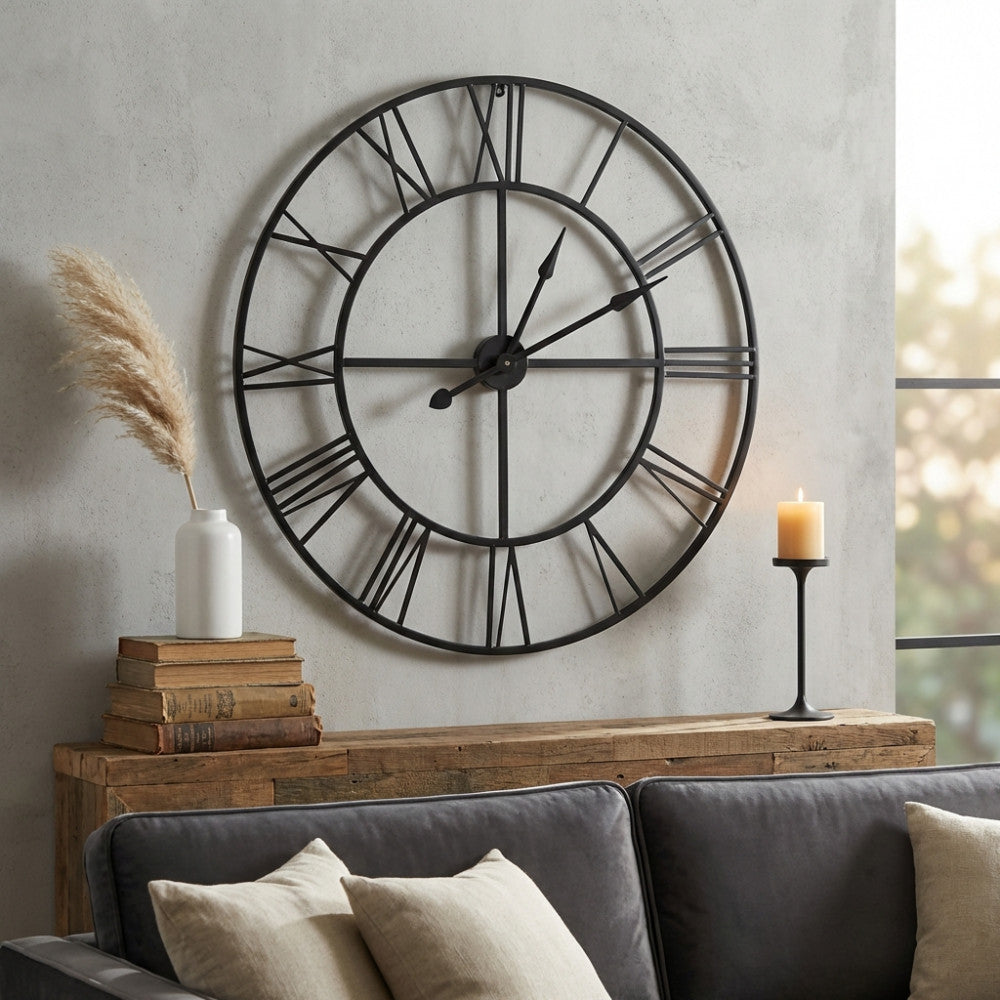 Dettaglio dell'orologio vintage in metallo scuro inserito in un soggiorno elegante con divano in velluto grigio e decorazioni minimaliste.