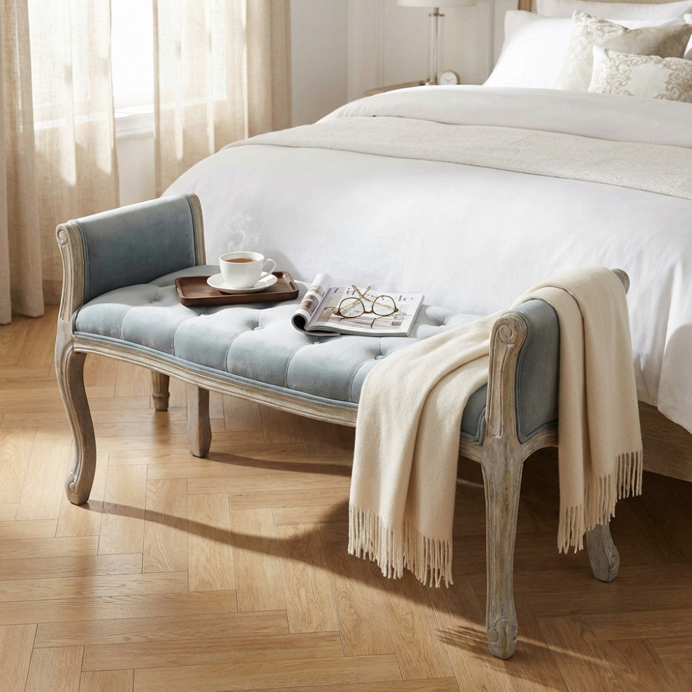 Dettaglio della panca in velluto grigio con un vassoio in legno, una tazza e una morbida coperta.