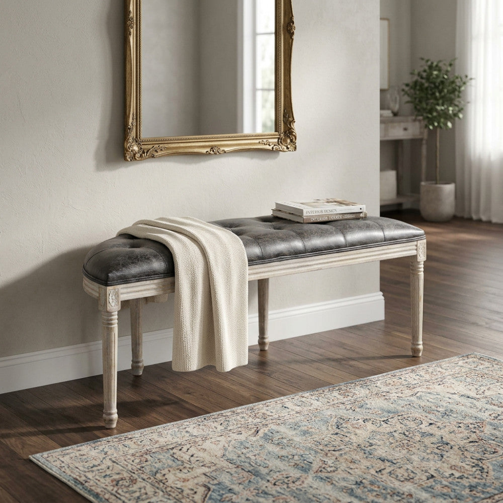Vista angolare della panca Margi in ecopelle e legno, decorata con una coperta in maglia chiara.