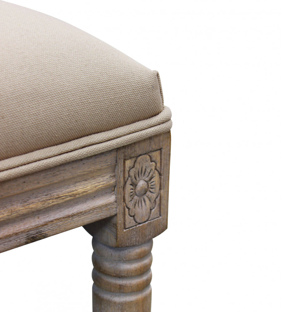 Dettaglio dell'intaglio floreale sul legno e della cucitura del tessuto beige.