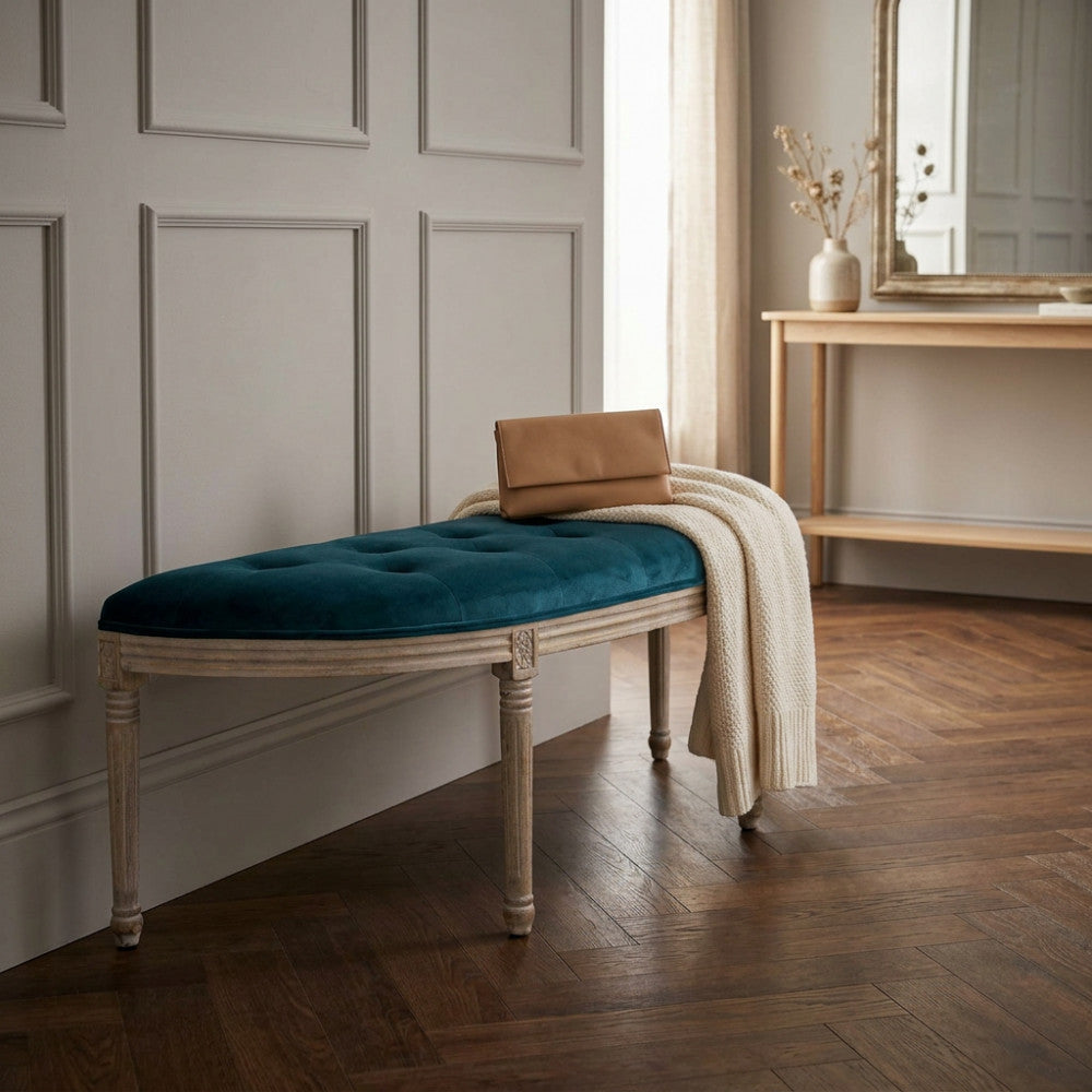 Dettaglio della panca in velluto blu con una borsa in pelle e una coperta chiara appoggiate sopra.
