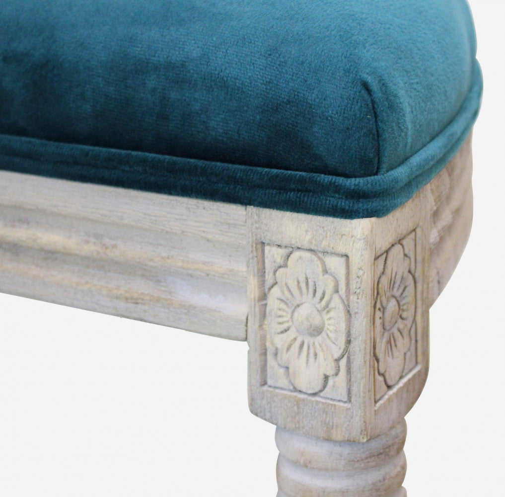 Dettaglio ravvicinato della gamba in legno intagliato con motivo floreale e del bordo in velluto blu.