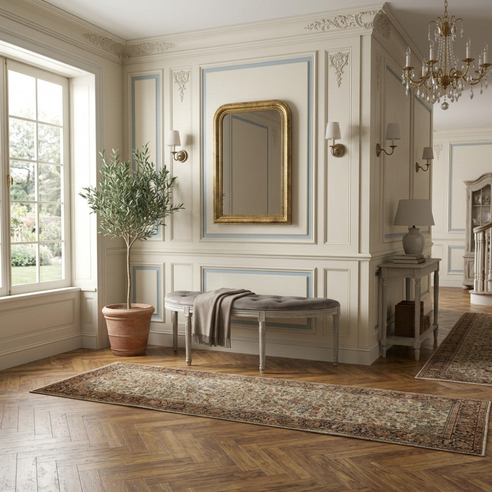 Panca Margi in velluto taupe posizionata in un ingresso classico con specchio dorato e pavimento in parquet.