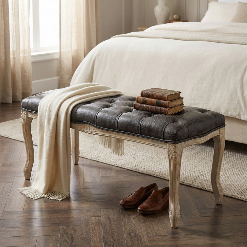 Dettaglio della panca da interno Misty con libri antichi e una coperta in lana appoggiati sulla seduta capitonnè.